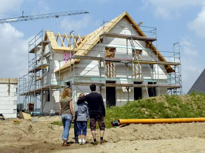 Drei Personen vor einer Hausbaustelle